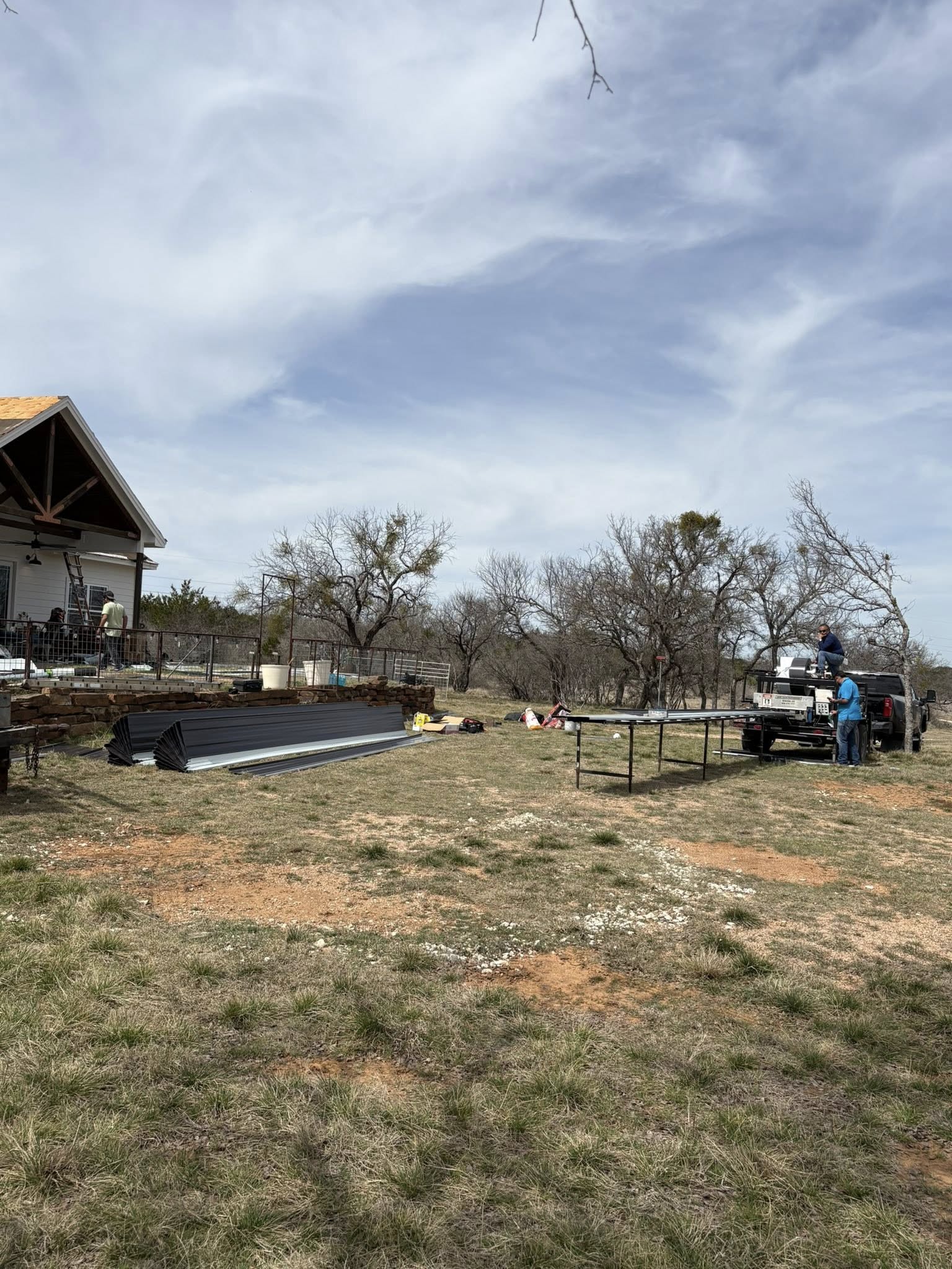 Roofing site setup with flatbed trailer on rural property